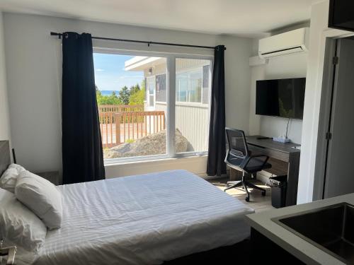a bedroom with a bed and a desk and a window at Complexe la Falaise in Rivière-du-Loup