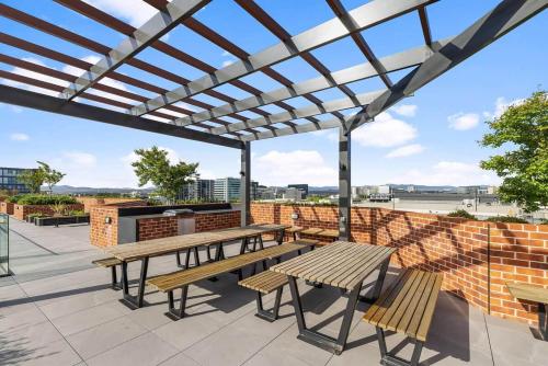 a patio with wooden benches and a pergola at Central 2b2b with 2 Parkings across largest Mall in Braddon