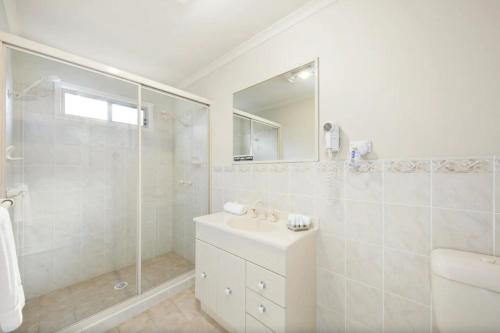 a white bathroom with a sink and a shower at Palmers Lane Vineyard Cottage in Pokolbin