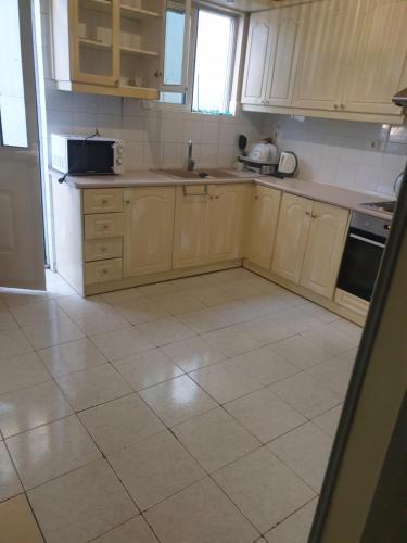 a kitchen with wooden cabinets and a tile floor at O&M Port Piraeus in Piraeus