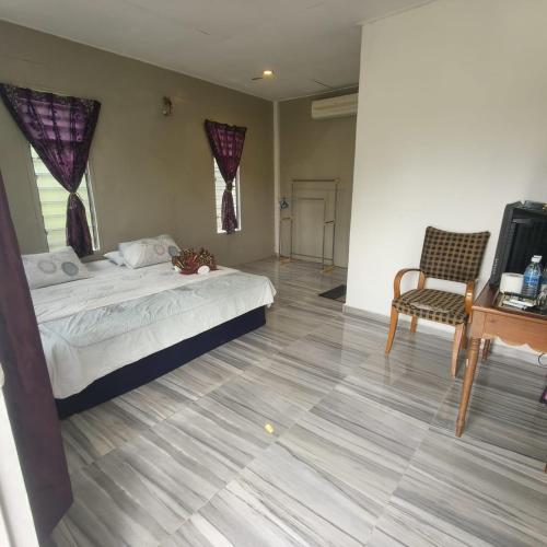 a bedroom with a bed and a table and a chair at Kurau Stone Chalet in Taiping