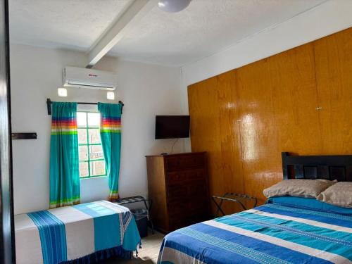 a bedroom with two beds and a window with a rainbow curtain at Hostal Mixteco Naba Nandoo in Oaxaca City