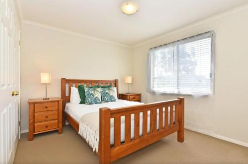 a bedroom with a wooden bed and a window at Palmers Lane Vineyard Cottage in Pokolbin