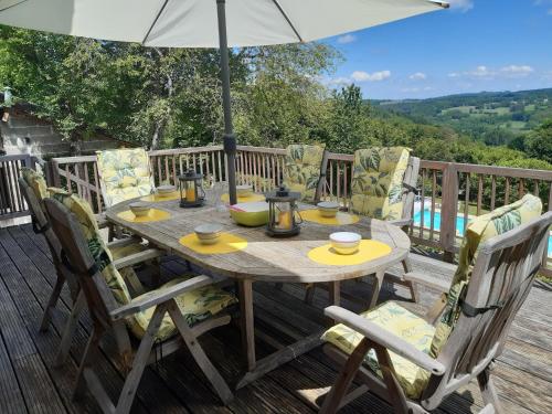 a wooden table with chairs and an umbrella on a deck at Holiday Home in Limoges with Saltwater Pool in Châteauneuf-la-Forêt