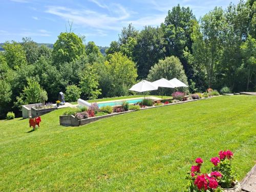 a lawn with a swimming pool and umbrellas at Holiday Home in Limoges with Saltwater Pool in Châteauneuf-la-Forêt
