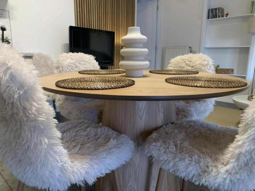 a table with four white furry chairs around it at Sunny Cottage with Pool in Purnode