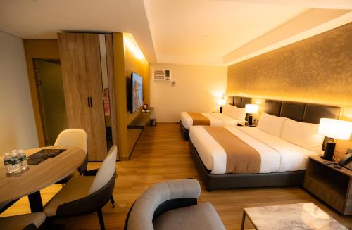 a hotel room with two beds and a table and chairs at Vibe Hotel Alabang in Manila