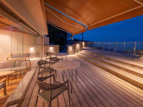 a patio with tables and chairs on a deck at night at Hamabenoyado Kameya in Toba