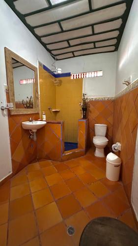 an orange tiled bathroom with a toilet and a sink at Eco Finca El Regalo in Salento