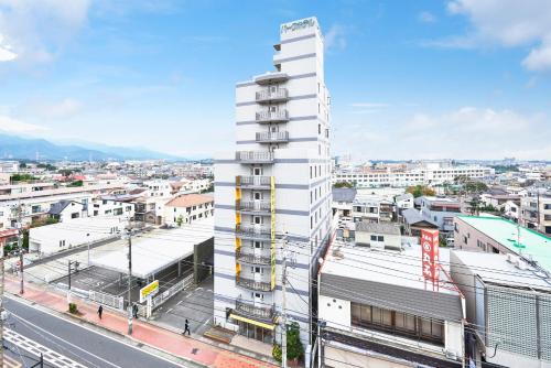 a tall white building next to a city at Hotel Select Inn Isehara in Isehara