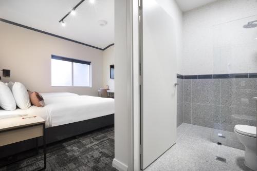 a bedroom with a bed and a shower at Nightcap at Wanneroo Tavern in Wanneru