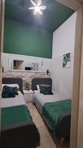 two beds in a room with green and white walls at The Village Retreat in Malona Village