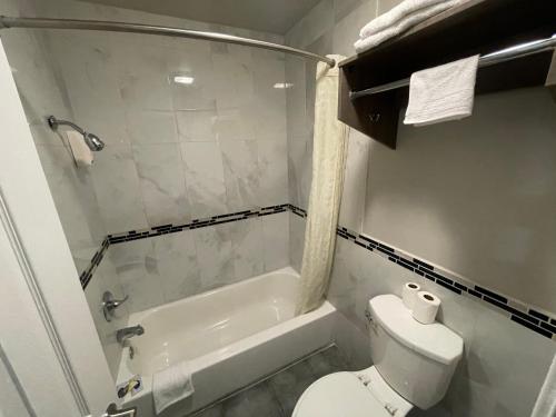 a bathroom with a toilet and a shower and a tub at SimpleStay Suites - Downtown San Bernardino in San Bernardino