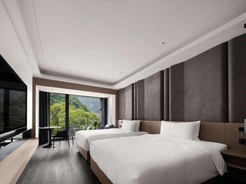 a bedroom with two beds and a large window at Mercure Guilin Yangshuo Xingping in Guilin