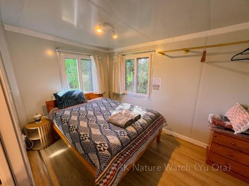 a bedroom with a bed and two windows at AAK cabin - standalone riverfront cabin in Malanda