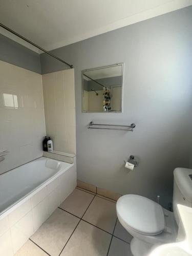 a bathroom with a toilet and a tub and a sink at Iluka in Yeppoon