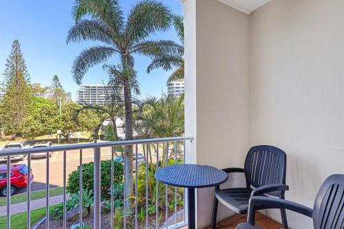 a balcony with two chairs and a table and a palm tree at Elouera Tower in Maroochydore