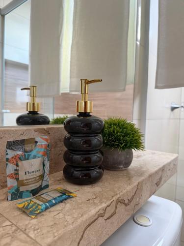 a bathroom counter with a black and gold bottle on it at Apartamento completo in Nova Mutum