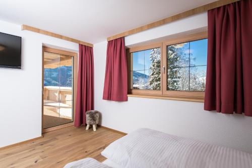 a bedroom with a bed and a window with red curtains at Ferienwohnungen H&P in Alpbach