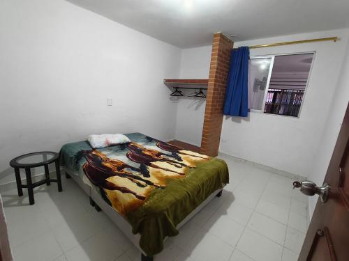 a bedroom with a bed and a table and a window at Felipe's House in Ibagué