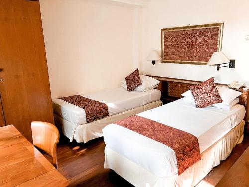 a hotel room with two beds and a chair at Club Bali Suite Legian in Legian