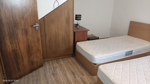 a small bedroom with two beds and a wooden door at Casa Bisavós de Coelhosa in Vale de Cambra