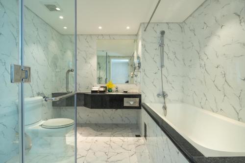a bathroom with a tub and a toilet and a sink at Windsor Plaza Hotel in Ho Chi Minh City
