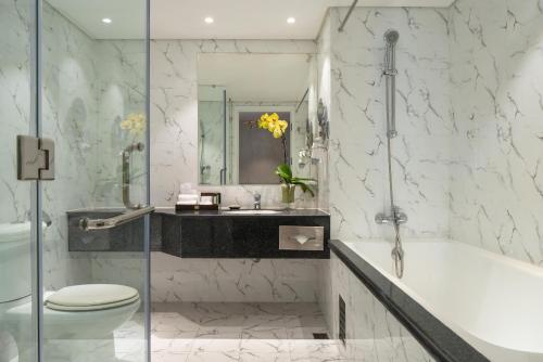 a bathroom with a tub and a toilet and a sink at Windsor Plaza Hotel in Ho Chi Minh City