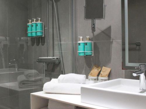 a bathroom with a sink and a shower with towels at Novotel Narbonne Sud A9/A61 in Narbonne