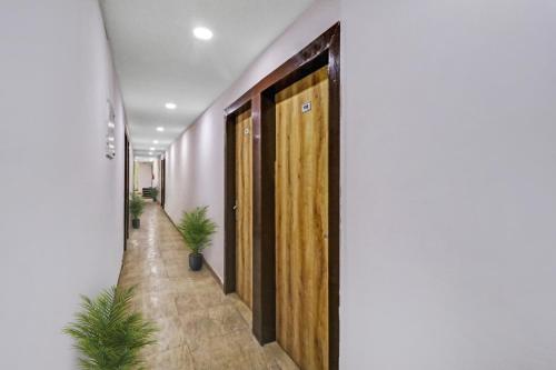 a hallway with wooden doors and potted plants at Hotel O Fox Guest House in Greater Noida