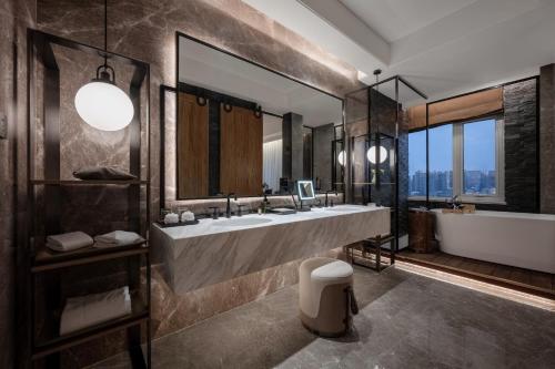 a bathroom with two sinks and a tub and a large mirror at Rainbird Hotel in Chengdu