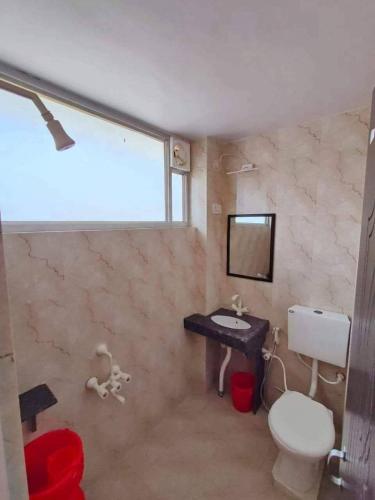 a bathroom with a toilet and a sink and a mirror at Adharshila hotel & Dormitory in Shahdol