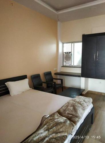 a bedroom with a large bed and two chairs at Adharshila hotel & Dormitory in Shahdol