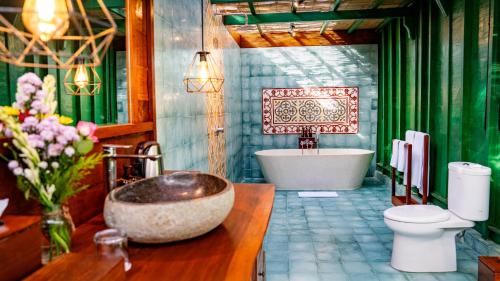 a bathroom with a tub and a toilet and a sink at Juwel Villa Ubud in Ubud