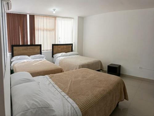 a room with three beds and a window at Hotel the Blue House in Ipiales