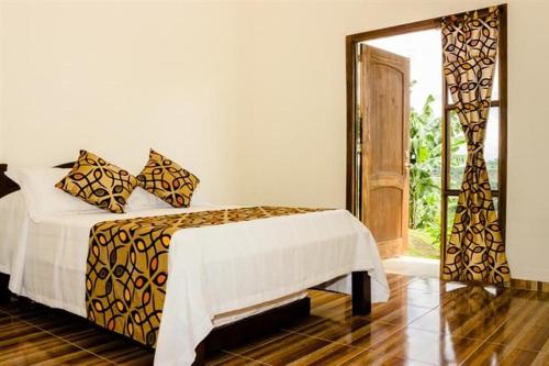 a bedroom with a bed and a sliding glass door at Riverwalk cabañas junto al rio in Calarcá