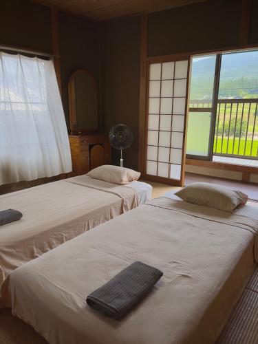 two beds in a room with two windows at Homestay HANIHOHETO in Ena