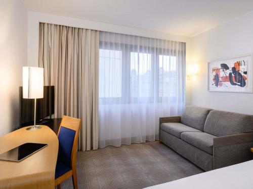 ein Wohnzimmer mit Sofa und einem Tisch mit Schreibtisch in der Unterkunft Novotel Gdansk Centrum in Danzig