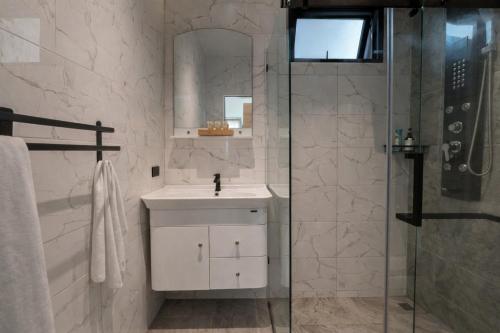 a white bathroom with a sink and a shower at ArtiZen Hideout near Hin Kong Beach in Hinkong