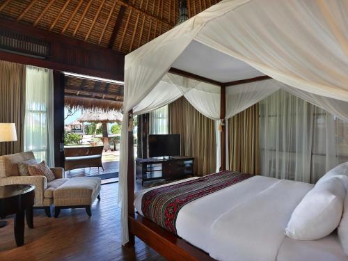 a bedroom with a canopy bed and a living room at Novotel Lombok Resort & Villas in Kuta Lombok