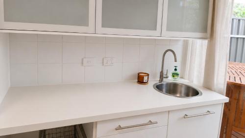 a kitchen with a sink and white cabinets at Verandah Suite in Seacliff