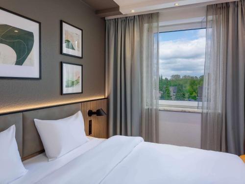 a bedroom with a white bed and a window at ibis Paderborn City in Paderborn