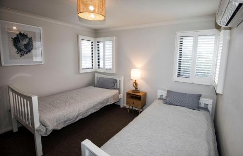 a bedroom with two beds and two windows at Flinders Rest in Queenscliff