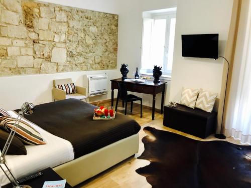 a bedroom with a bed and a desk and a table at I Santi Coronati in Siracusa