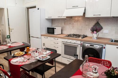 una cucina con due tavoli e una cucina con armadi bianchi di A Casa di Benny a Roma