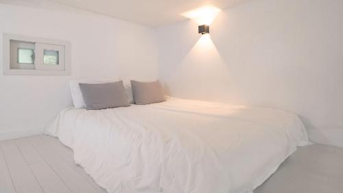 a white bed in a white room with a light at Gapyeong Shiny Pension in Gapyeong