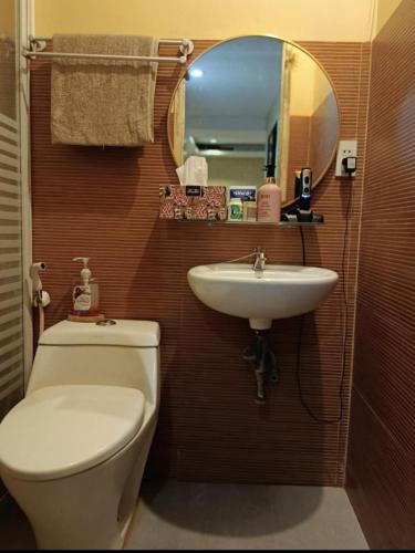 a bathroom with a toilet and a sink and a mirror at Nonoy's Haven in Dipolog