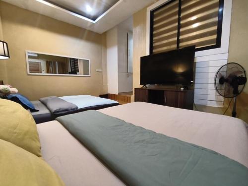 a bedroom with two beds and a flat screen tv at Nonoy's Haven in Dipolog
