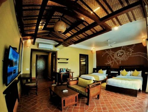 a hotel room with two beds and a living room at Green Park Chitwan in Sauraha