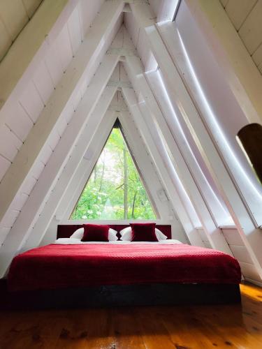 a bedroom with a red bed with a window at PiatrA Frame in Ştefeşti